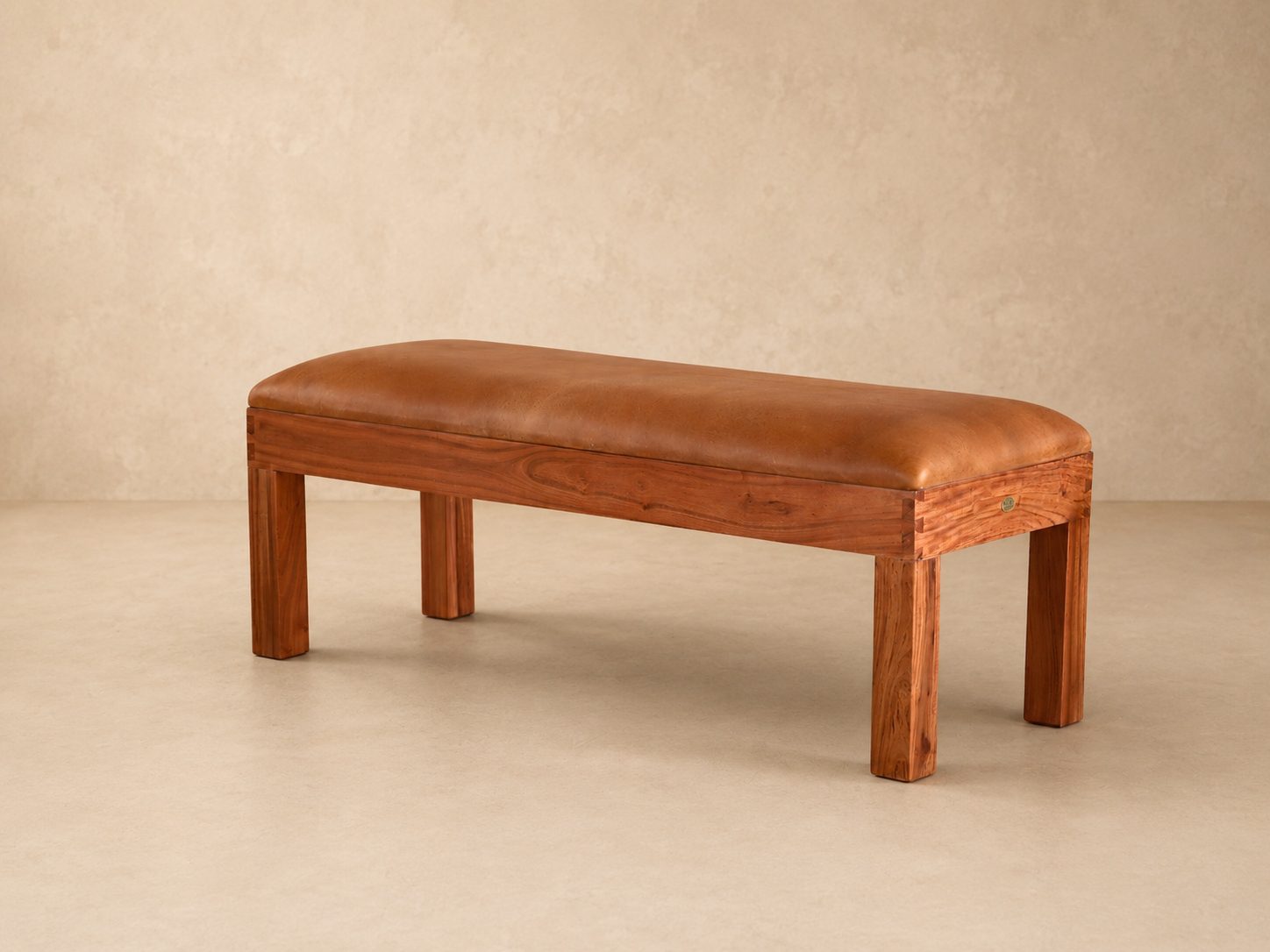 Burchell Upholstered Leather Bench 4 Three-quarter view of the Burchell leather bench with tan leather cushion, handcrafted wooden frame and natural wood grain.