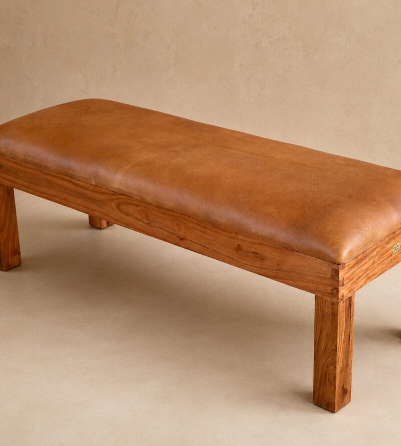 Front end view of the Burchell leather bench showing the tan leather cushion, wooden legs and African Touch badge.